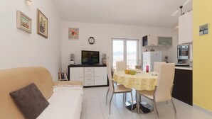 A compact living space with a sofa, a dining table with chairs, a kitchen area with appliances, and a large window. - Amazing apartment in Pag with house sea view (Pag)