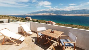 A terrace with a table and chairs, overlooking a coastal landscape with mountains and a body of water. - Amazing apartment in Pag with house sea view (Pag)