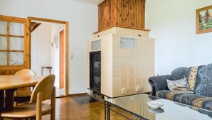 A living room with a glass coffee table, a sofa, a wooden dining table with chairs, and a built-in oven. - Gorgeous apartment in Prerow with WiFi (Prerow)