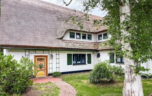 Ein traditionelles Haus mit Strohdach, weißen Wänden und grünen Fensterläden.