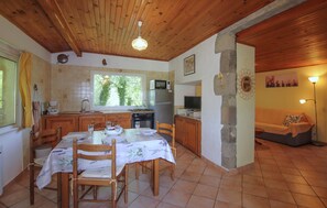 Una cucina con mobili in legno, un tavolo da pranzo per quattro persone e un'ampia finestra.
