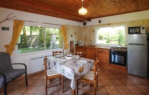 A kitchen with a dining table set for four, wooden cabinets, a stove, and a refrigerator. - Lovely home in St. Etienne de Boulog. (St. Etienne de Boulog.)