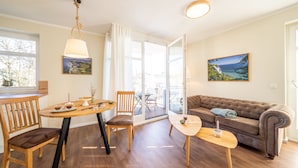 Ett modernt vardagsrum med ett matbord i trä, en soffa och ett stort fönster med utsikt.