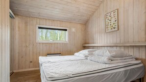 Ett rum med träpanel på väggarna, en säng, ett fönster och en affisch med bilder på olika frukter.