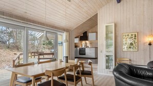 Ett modernt kök med vita skåp, en svart ugn och en matplats med möbler i trä.