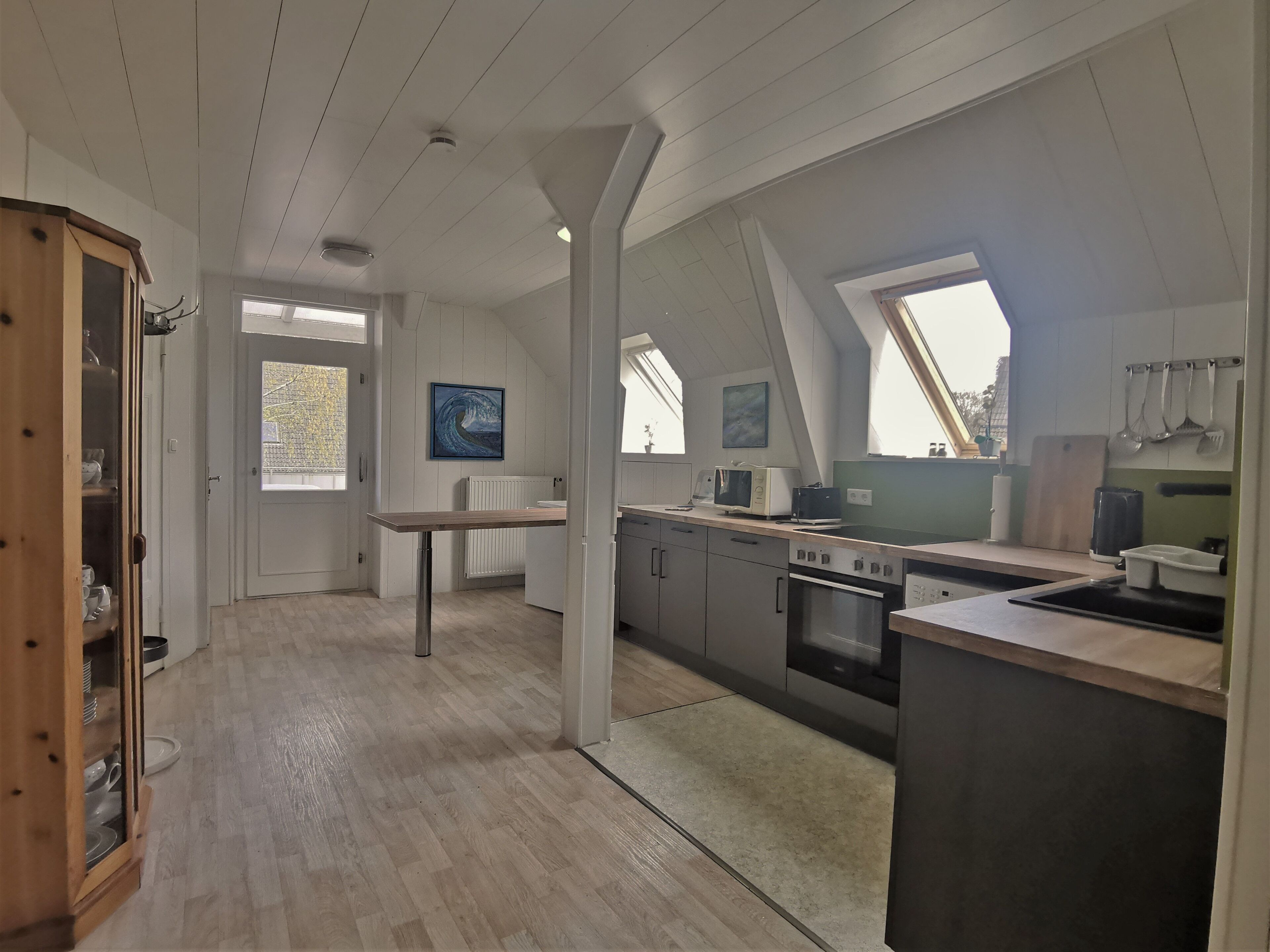 Ett modernt kök med ett träskåp, ett matbord och utsikt över omgivningen.