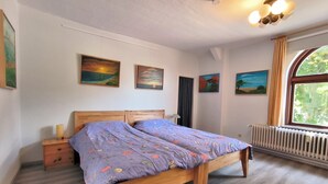 Ein Schlafzimmer mit einem hölzernen Bett, einem Nachttisch, einem Heizkörper und drei Bildern an der Wand.