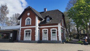 Ein zweistöckiges Backsteingebäude mit weißem Zierrat und einem dunkel gefliesten Dach.
