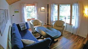 A cozy living room with a blue sofa, two armchairs, a coffee table, and large windows with curtains. - Stunning home in årjäng with WiFi (Årjäng)