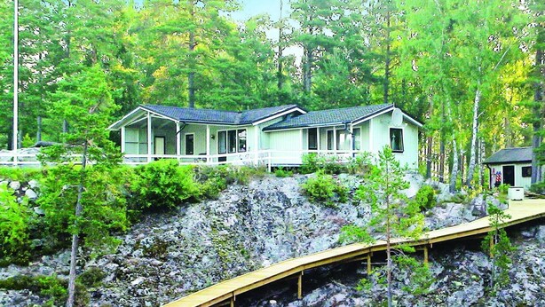 A two-story house with a covered porch, surrounded by dense forest and rocky terrain. - Stunning home in årjäng with WiFi (Årjäng)