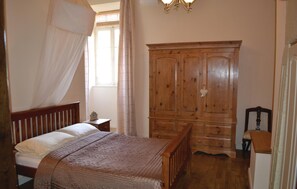 Une chambre à coucher avec un lit, une armoire en bois et une table de chevet.