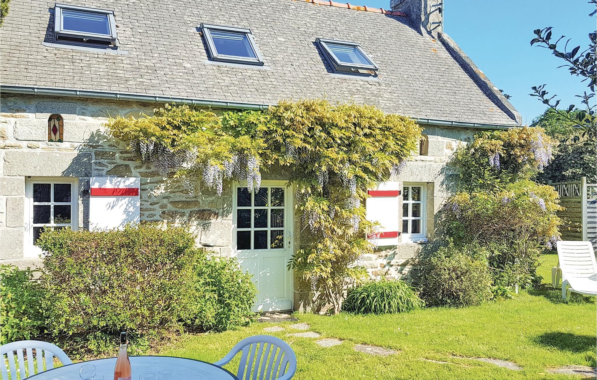 A stone house with a garden, a table with chairs, and a clear sky.