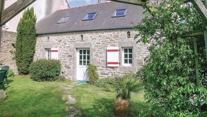 A stone building with a tiled roof, a door, and windows with shutters. There is a grassy area with a pathway leading to the door. - 1 bedroom lovely home in Douarnenez (Douarnenez)