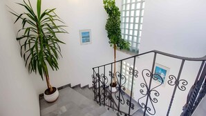 A staircase with a railing, potted plants, and framed pictures on the walls.