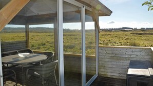 Un espacio al aire libre cubierto con una mesa, sillas, una parrilla y vistas a un campo verde.
