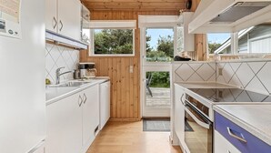 Una cocina moderna con techo de madera, armarios blancos y vistas al exterior.