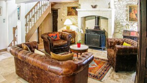 A traditional living room with leather sofas, a fireplace, and a staircase. - Amazing home in Les Farges (Les Farges)