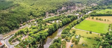 An aerial view of a town with a river, green fields, and a bridge.