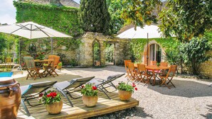 An outdoor patio with wooden furniture, potted plants, and a stone wall. - Amazing home in Les Farges (Les Farges)