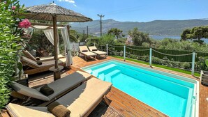 Ein Poolbereich mit Liegestühlen und einer Pergola, umgeben von Grün und Blick auf die Hügel.