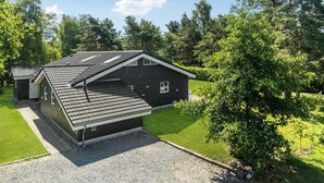 Une maison moderne à deux étages, dotée d’un toit en pente, d’un petit garage attenant et d’une pelouse bien entretenue.