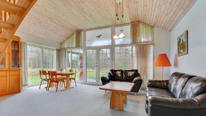 Un vaste salon doté d’un plafond en bois, d’un canapé en cuir, d’une table basse et d’un coin repas avec une table et des chaises.