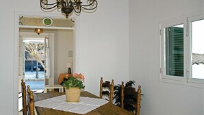 A dining area with a wooden table, chairs, a chandelier, and a window with shutters.