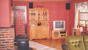A living room with a brick fireplace, wooden cabinet, television, and a green armchair. - 3 bedroom amazing home in Etne (Etne)