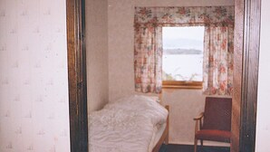 A bedroom with a single bed, a chair, and a window with floral curtains. - 3 bedroom amazing home in Etne (Etne)
