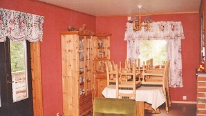 A dining room with a wooden cabinet, a green chair, and a dining table set for four. - 3 bedroom amazing home in Etne (Etne)