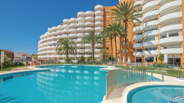 Un hotel con diversi balconi, una piscina e palme.