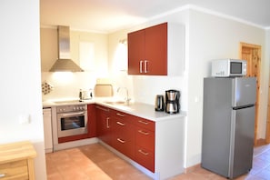A compact kitchen with a stove, oven, sink, and a refrigerator.
