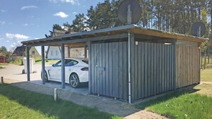 Ein kleines, eingeschossiges Gebäude mit überdachter Einfahrt und einem Auto darin.