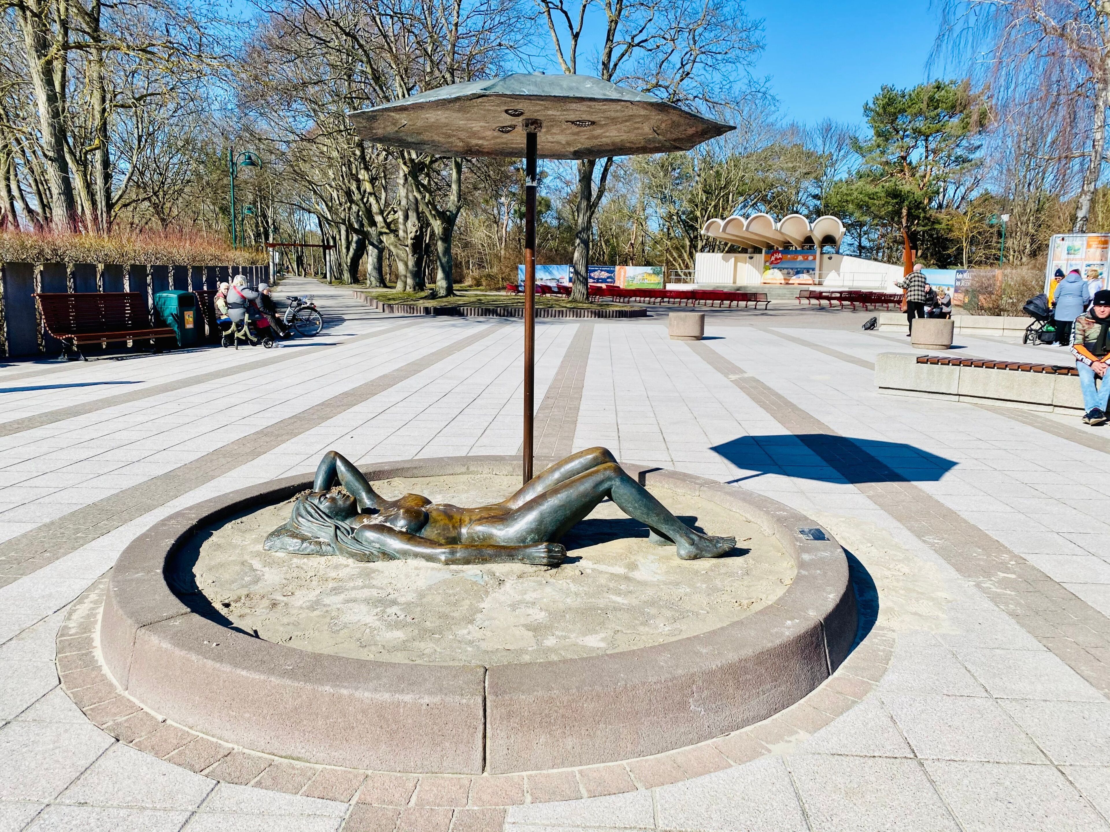 A public square with a circular seating area, benches, and a sculpture.