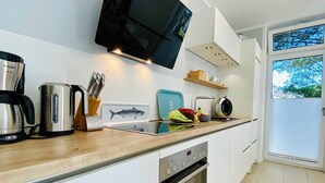 Una cucina moderna con forno integrato, macchina da caffè, bollitore e tagliere a tema pesce.