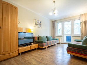 Un salon avec un meuble en bois, une télévision, un canapé et un fauteuil.
