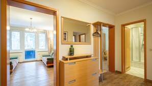Ein Hotelzimmer mit Holzboden, einem Bett mit gestreifter Bettdecke, einem Nachttisch mit grüner Vase, einem Spiegel über dem Tisch und einem Duschbereich mit Glastür.