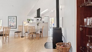 A modern kitchen with a black stove, wooden chairs, and a dining table. - Lovely home in Væggerløse with sauna (Væggerløse)