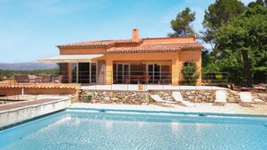 A Mediterranean-style villa with a swimming pool, stone walls, and a terrace with outdoor seating.