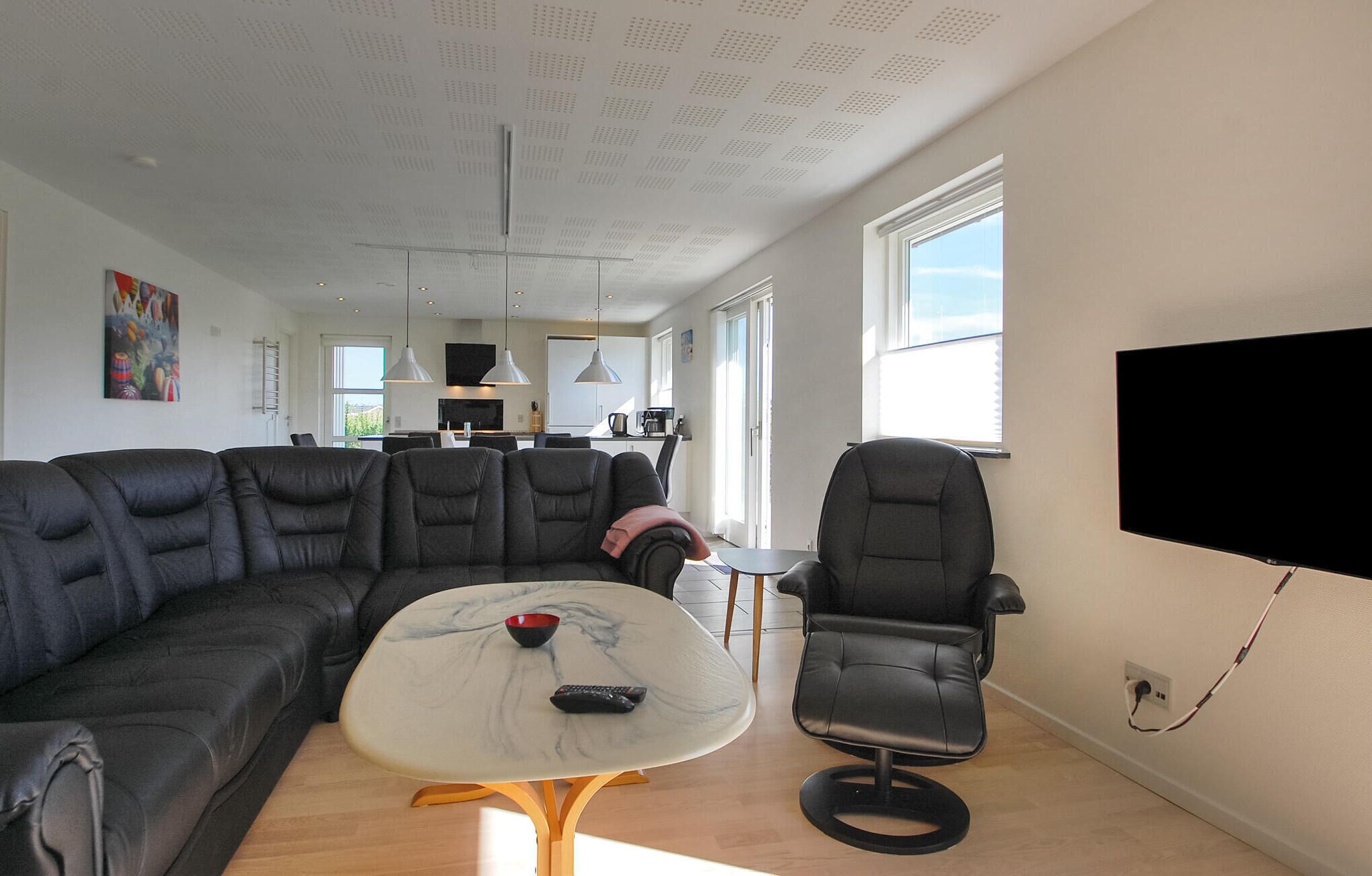 A modern living room with a sectional sofa, a small coffee table, and a TV mounted on the wall.