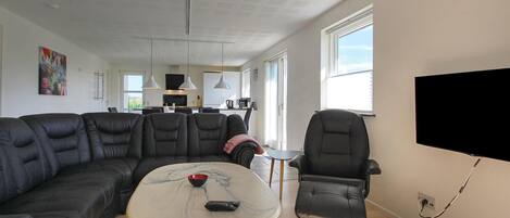 Un salon moderne avec un canapé d’angle, une petite table basse et un téléviseur fixé au mur.