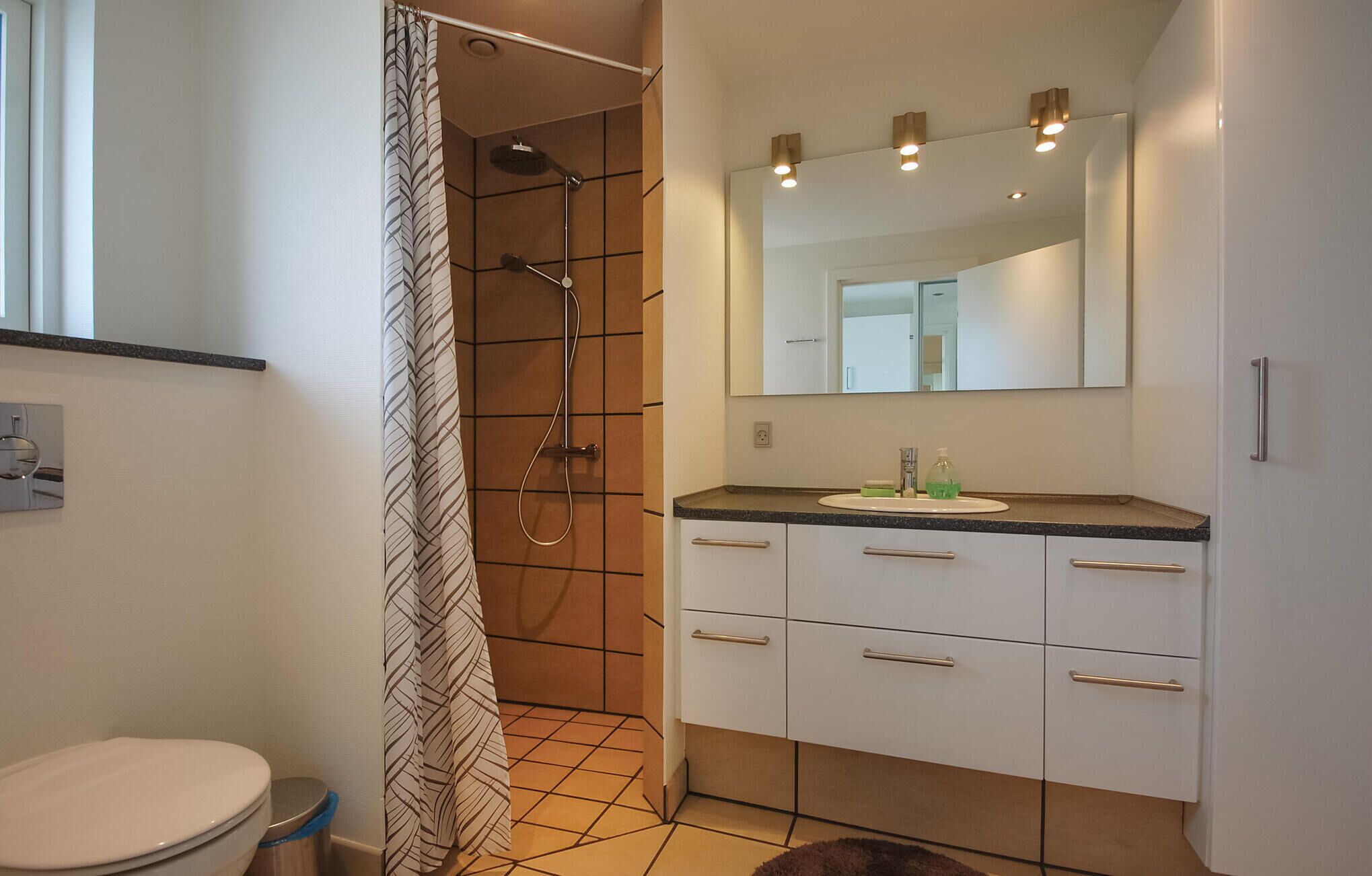 A bathroom with a shower, toilet, and sink.