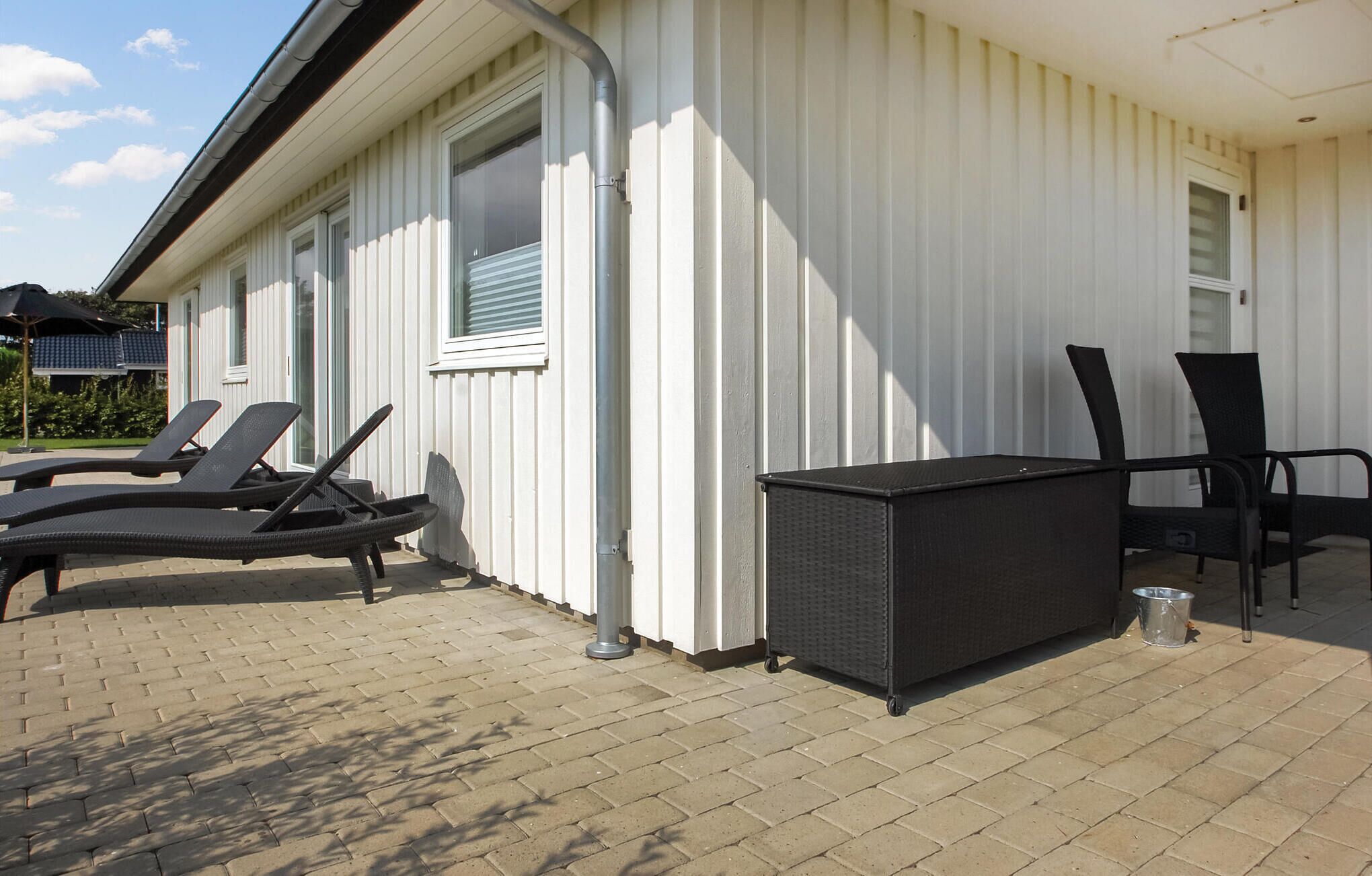 Un espace extérieur abrité, aménagé avec des chaises longues et une petite table, probablement une terrasse ou un patio.