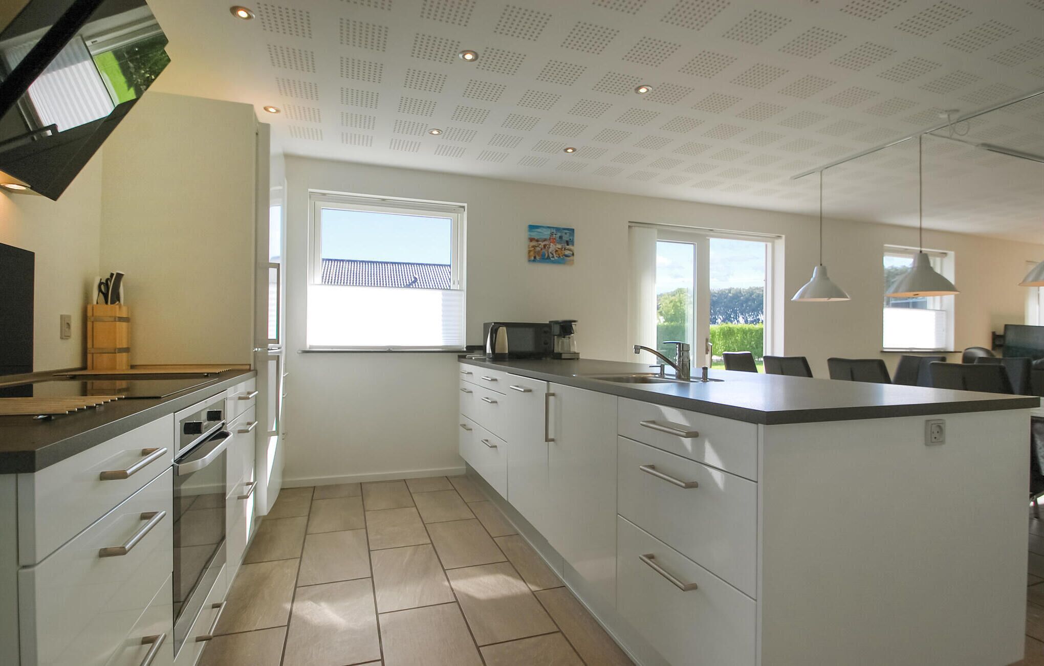 A modern kitchen with white cabinets, a large island, and a view of the outdoors.