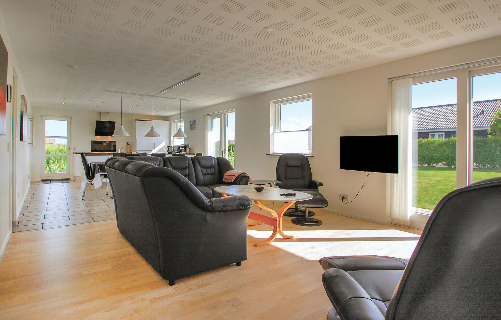 Ein modernes Wohnzimmer mit einer Sofagarnitur, einem Couchtisch und einem an der Wand befestigten Fernseher.