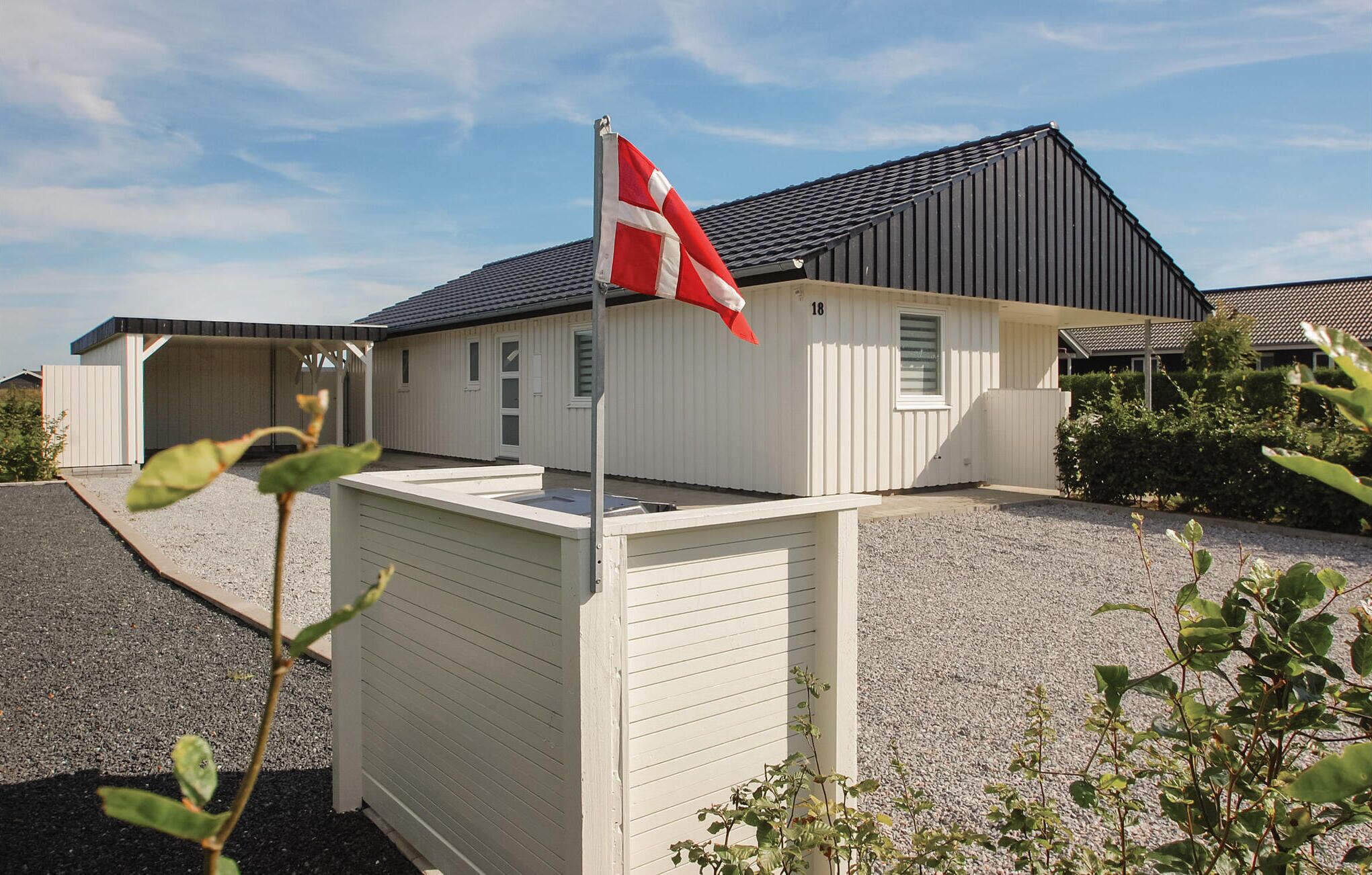 A single-story building with a sloped roof, a flagpole with a flag, and a gravel driveway.