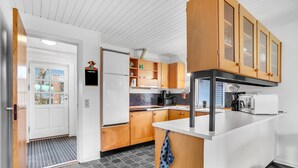 A modern kitchen with wooden cabinets, a white countertop, and a black microwave. - 2 bedroom beach front home in Tarm (Tarm)