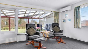 A room with two leather chairs, a small table, and a view of the outdoors through large windows. - 2 bedroom beach front home in Tarm (Tarm)