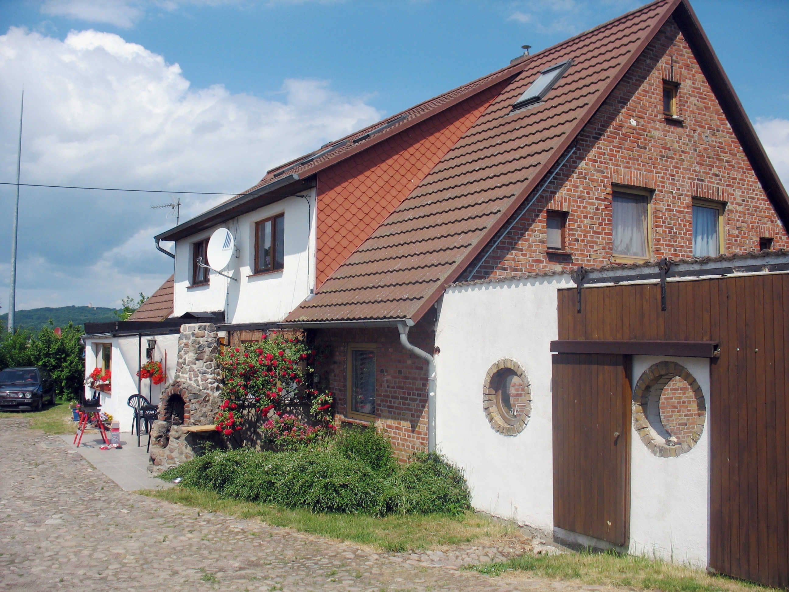 A traditional brick house with a sloped roof, a stone foundation, and a wooden door.