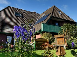 Una casa con techo inclinado, paneles solares y un balcón verde.